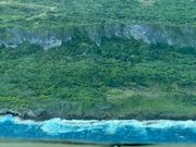 崖の緑と海の青の間に白い水しぶき